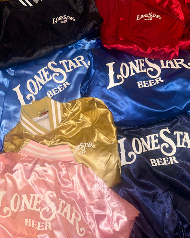 satin jackets of multiple colors, black, red, blue. gold, pink. Lone Star Beer across the back and breast. vintage look, stacked to show all colors